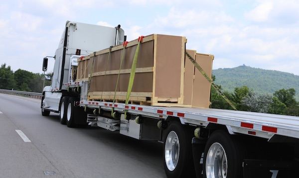 flatbed trailer with a heavy load strapped down driving on a Georgia highway