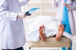 Police coroner examining dead body corpse in morgue.