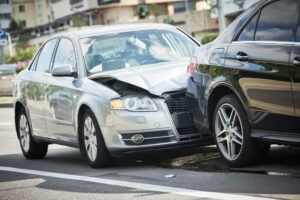 Rear end collision along the road involving black and silver cars.